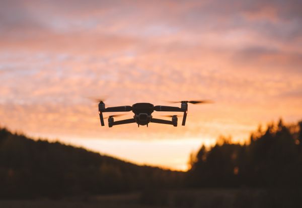 dron volando sobre un terreno con el atardecer de fondo