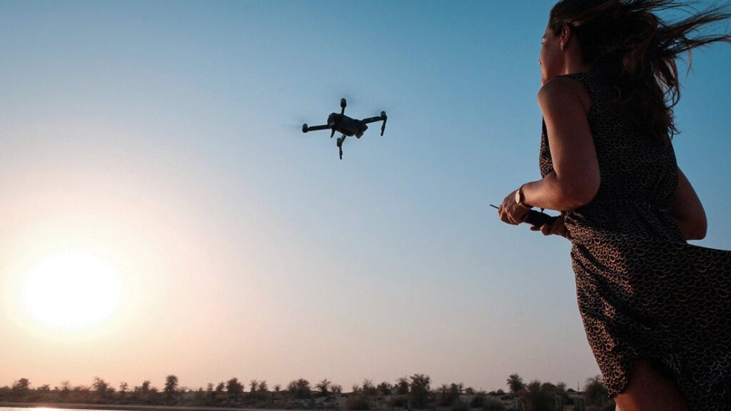 mujer volando un dron a contraluz