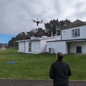 hombre volando un dron en un jardín privado frente a una cada blanca