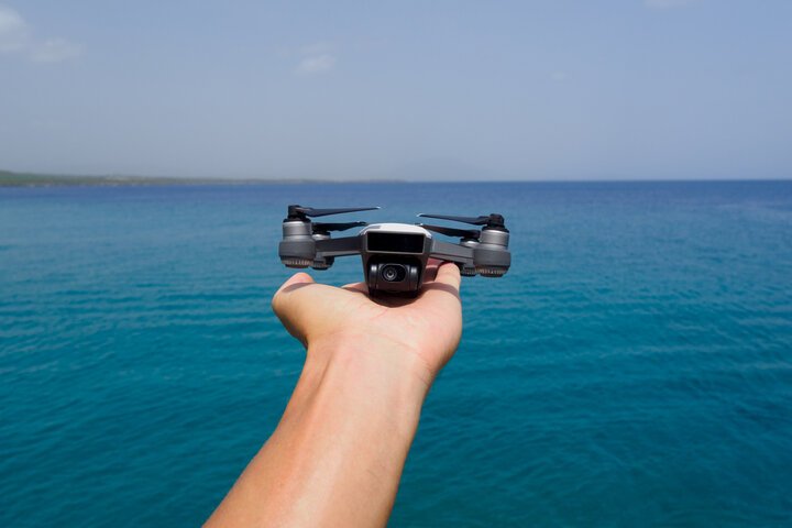 mano sujetando un dron con el mar de fondo