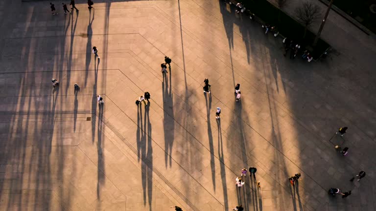 vista de la calle desde un dron, se aprecia a peatones y sus sombras durante el atardecer